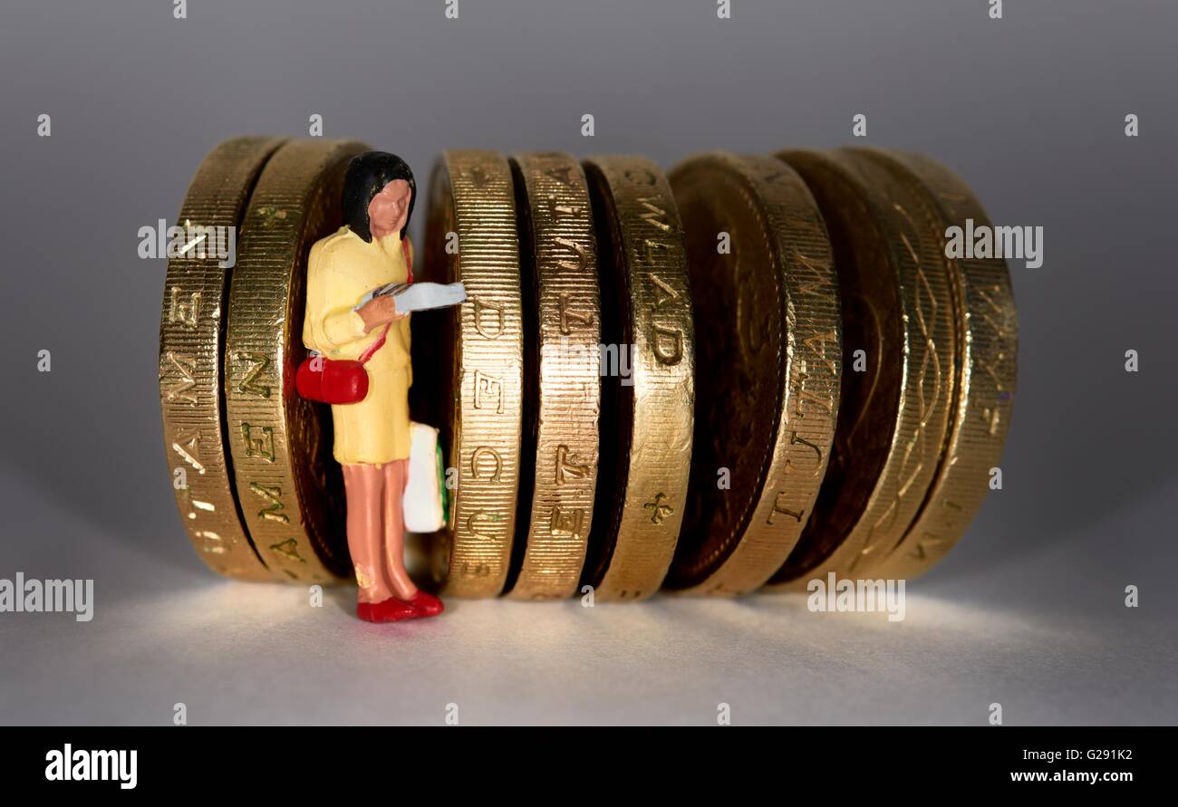 Statuetta in miniatura donna in piedi tra british una libbra di monete. Foto Stock