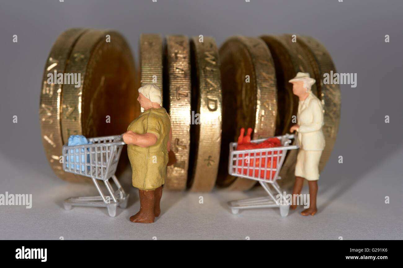Due figurine in miniatura donna anziana spingendo un supermercato carrello della spesa tra british una libbra di monete. Foto Stock