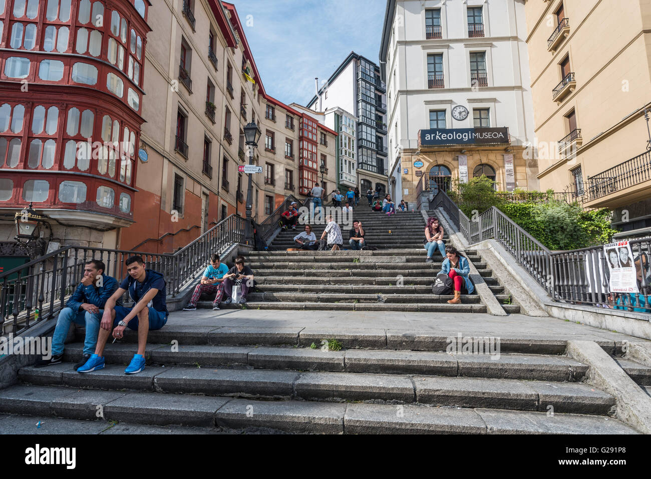 La gente seduta sui gradini che conducono fuori Miguel de Unamuno plaza, Casco Viejo, Bilbao, Spagna Foto Stock