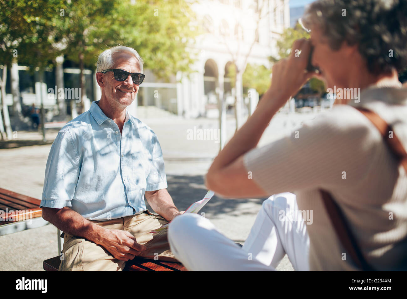 Bello il senior uomo fotografato da sua moglie. Senior tourist parlando di foto con la fotocamera all'aperto nella città. Foto Stock