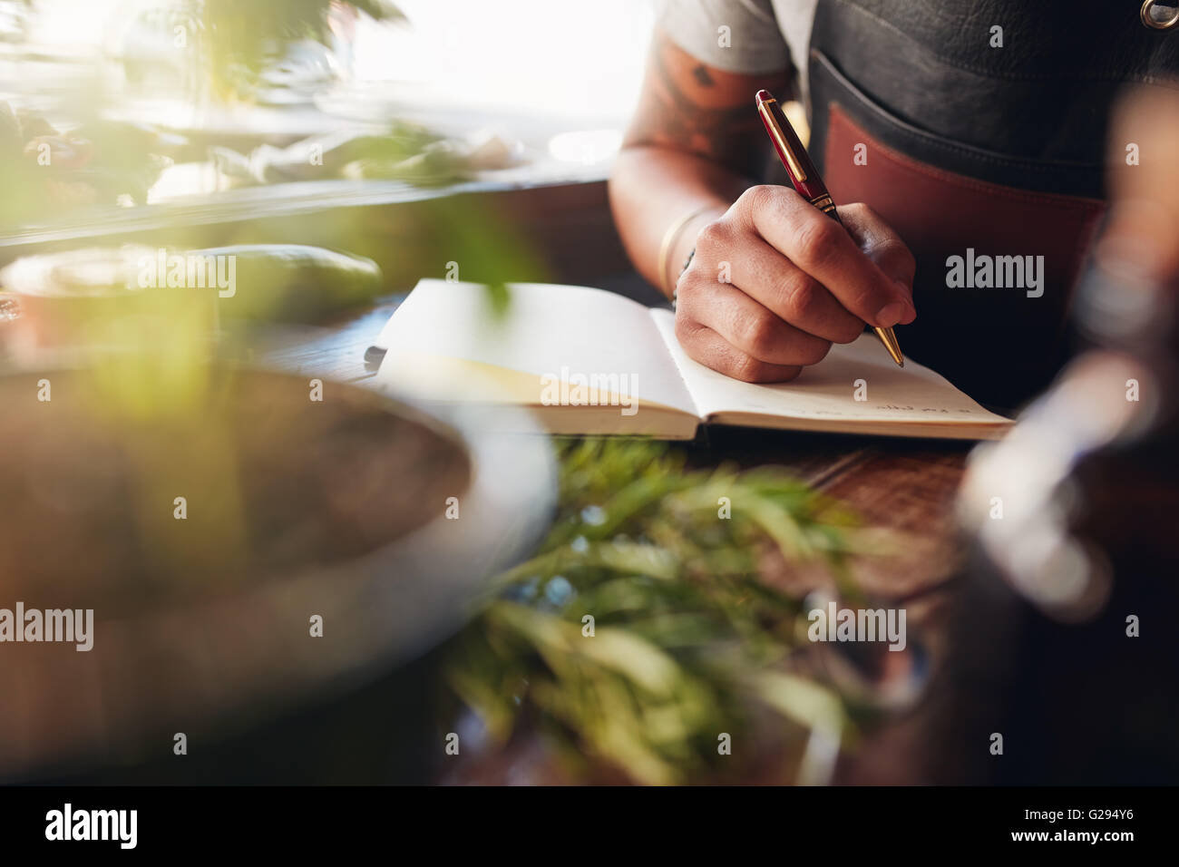Immagine ritagliata di barman scrivere le idee per la creazione di nuovi cocktail. Foto Stock