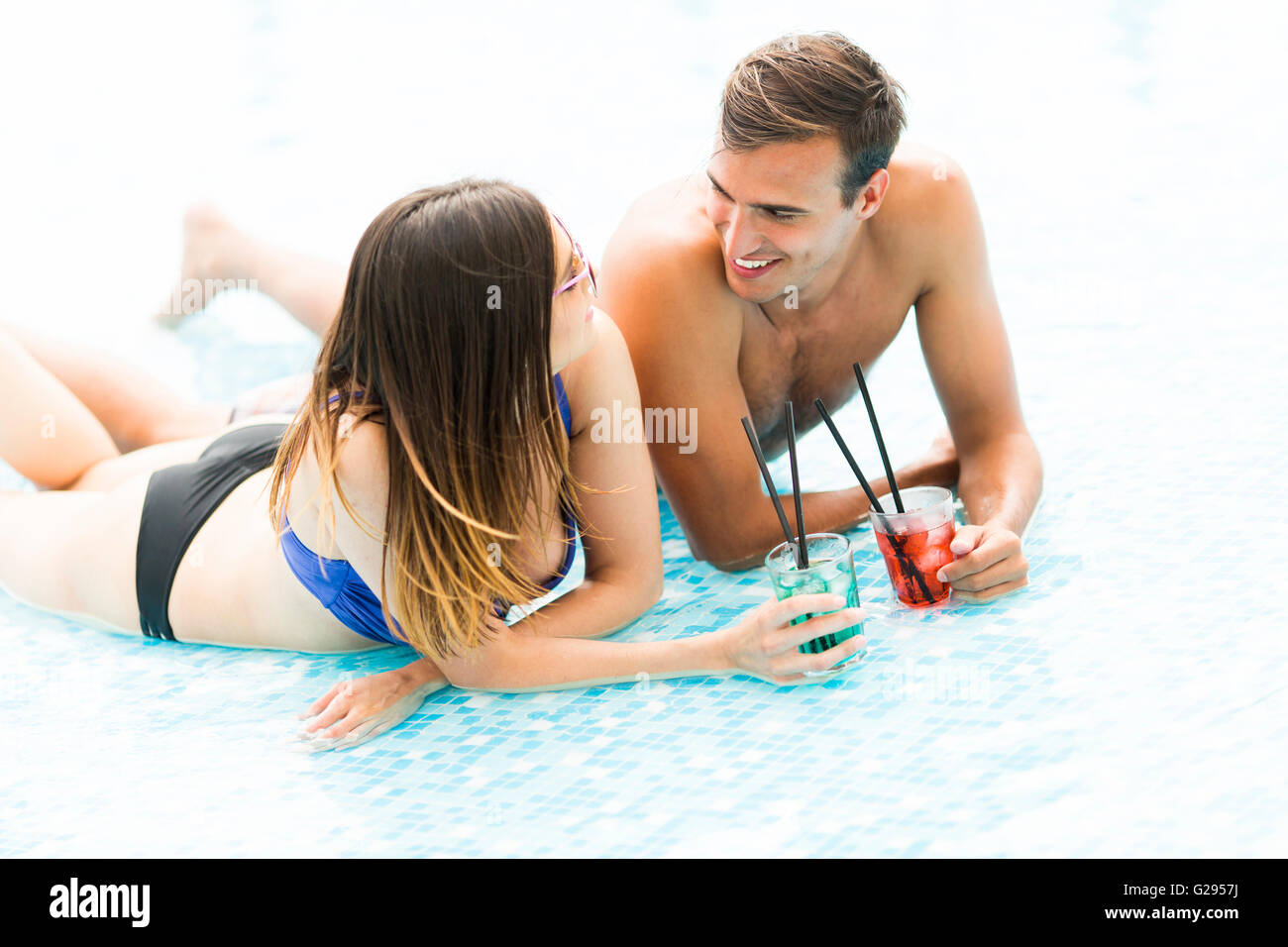 Coppia giovane di relax con un drink in piscina Foto Stock