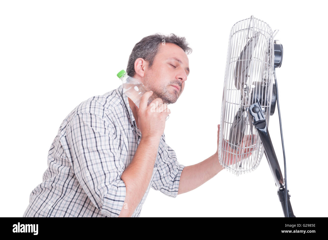 L'uomo raffreddamento nella parte anteriore del ventilatore di soffiaggio in possesso di una bottiglia di acqua fredda sul collo Foto Stock