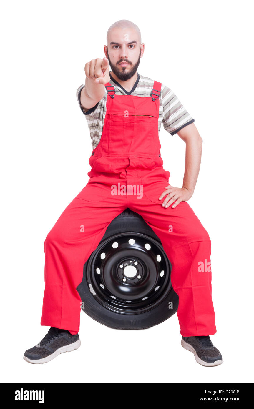 Mechanic poiting dito per il bianco della fotocamera seduti su auto ruota isolato su bianco Foto Stock