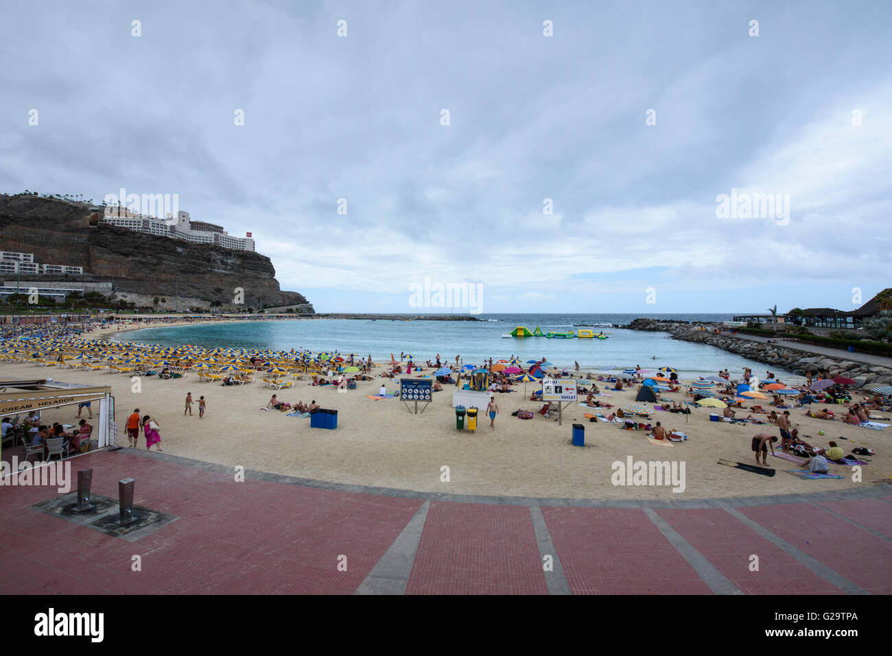 I turisti pack Amadores Beach a sud di gran canaria, nonostante il cielo nuvoloso Foto Stock