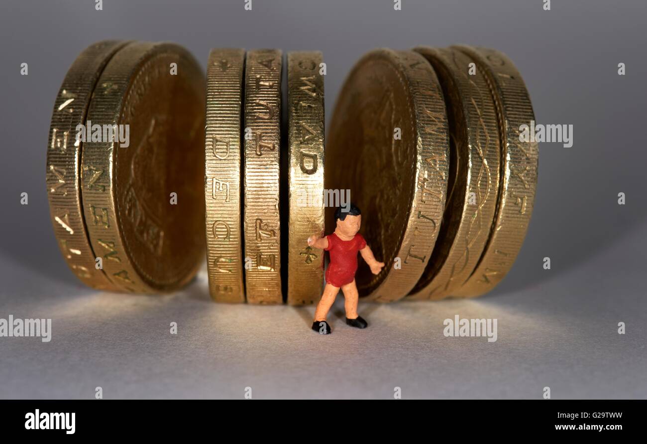 Una statuetta in miniatura in piedi piccolo ragazzo tra british una libbra di monete. Foto Stock