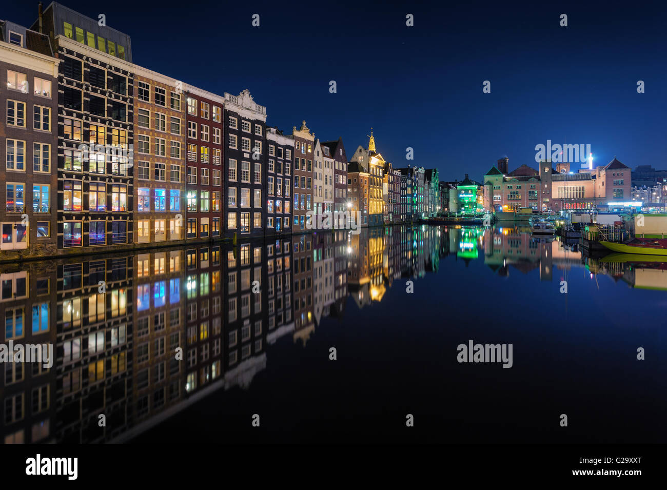 Bella tradizionali vecchie case di notte a Amsterdam, Paesi Bassi. Paesaggio con riflessi edifici della città in acqua con il colore blu Foto Stock