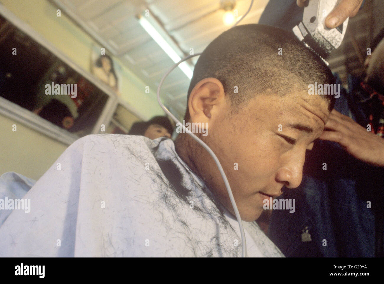 Un monaco tibetano si ottiene un taglio di capelli. Mcleod Ganj Dharamsala, Valle di Kangra, Himachal Pradesh, India. Foto Stock