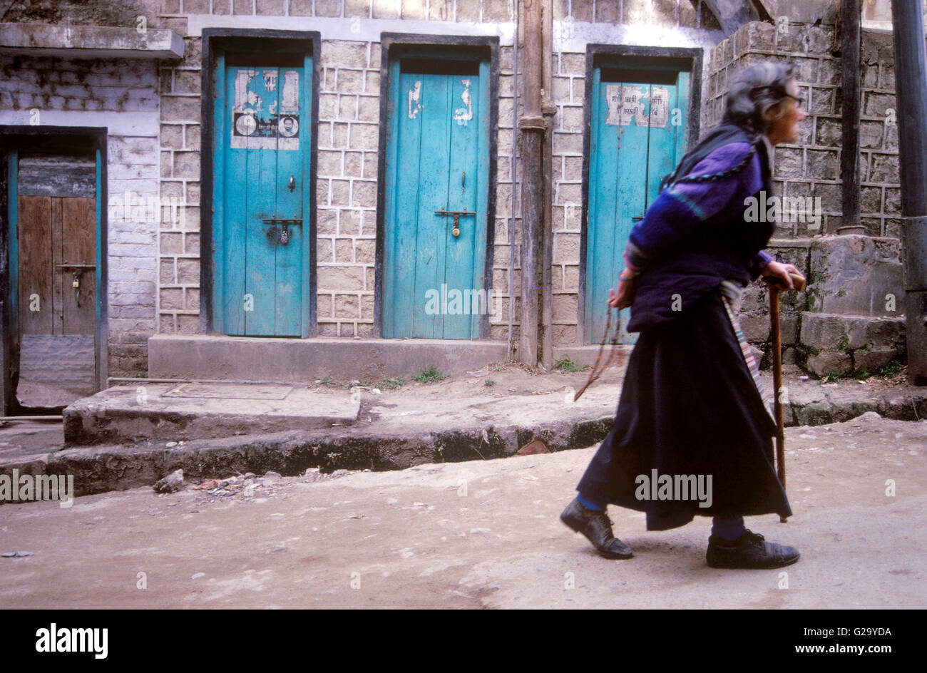 Un anziano tibetano donna cammina per le strade di McLeod Ganj mantenendo la sua preghiera talloni dietro la schiena.Dharamsala, India Foto Stock