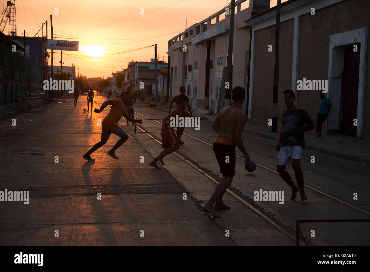 Sagome di adolescenti cubani giocando a calcio per strada come il sole tramonta dietro di loro a Cienfuegos Cuba Foto Stock