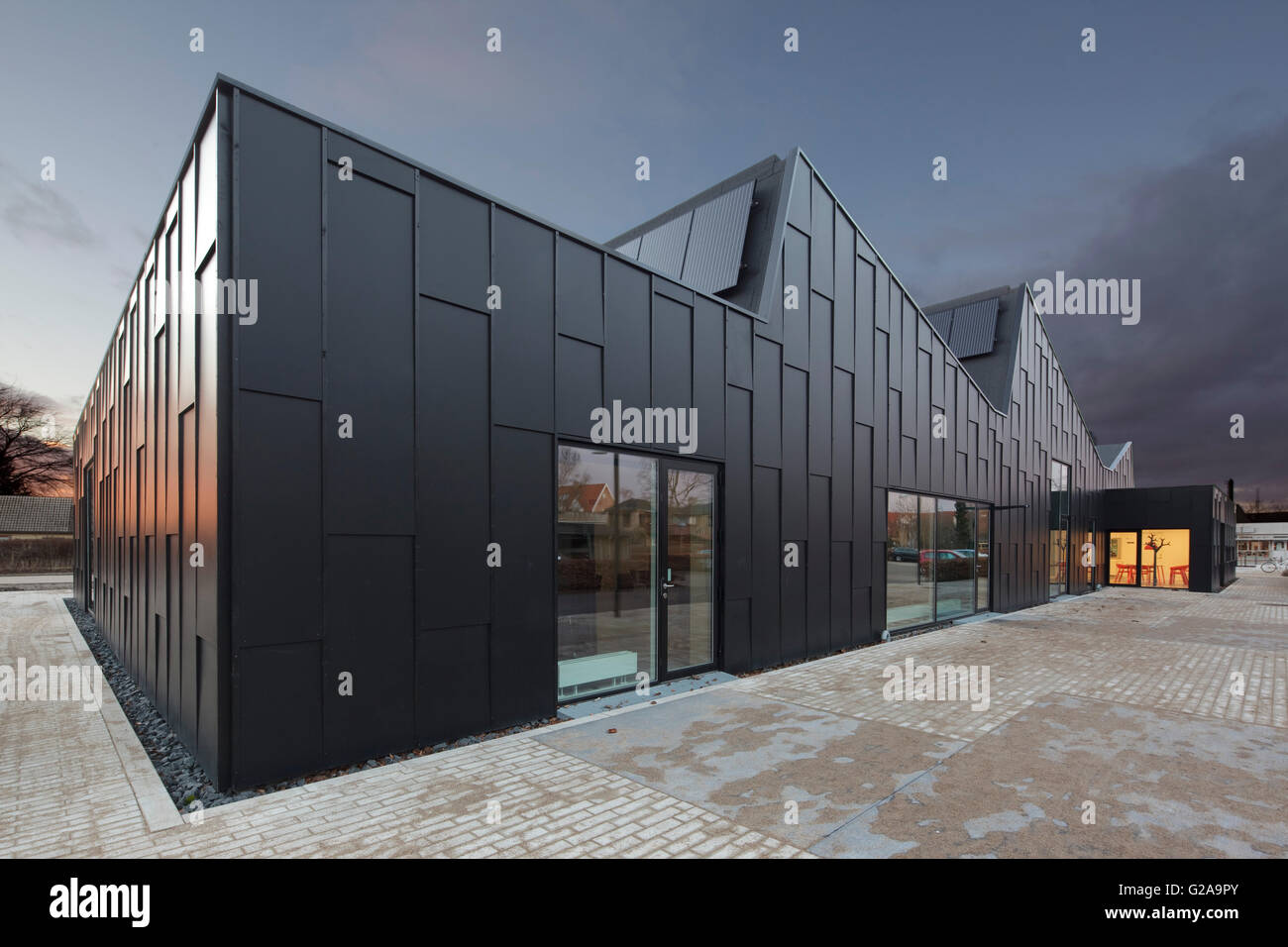 Esterno del prolungamento vestite di nero di pannelli in legno contro il cielo al tramonto. Libreria di Allerod, Allerod, Danimarca. Architetto: Primus Arkitekter , 2015. Foto Stock