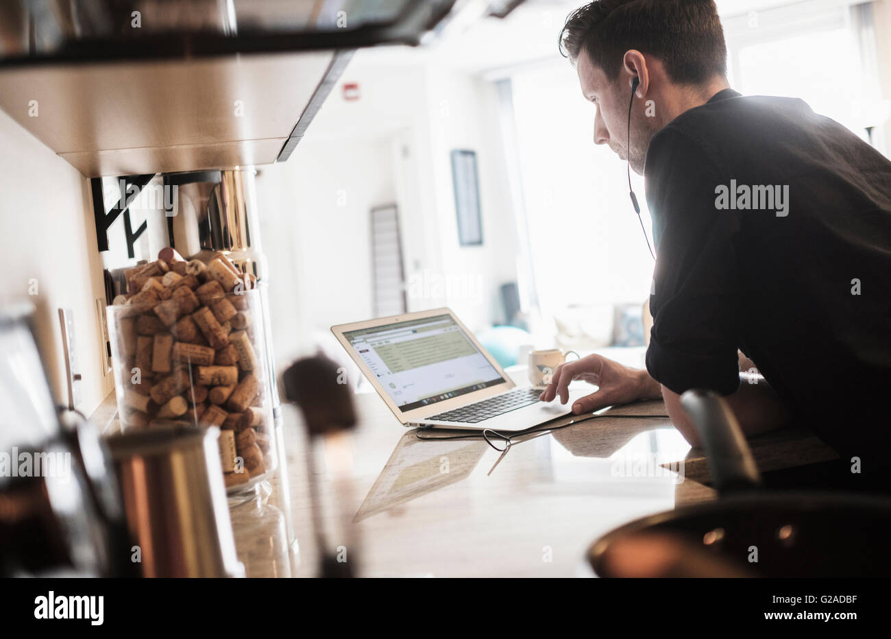 Uomo al lavoro su computer portatile in cucina Foto Stock