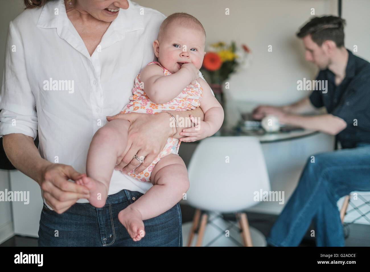 Azienda madre baby (2-5 mesi) e padre lavora in background Foto Stock