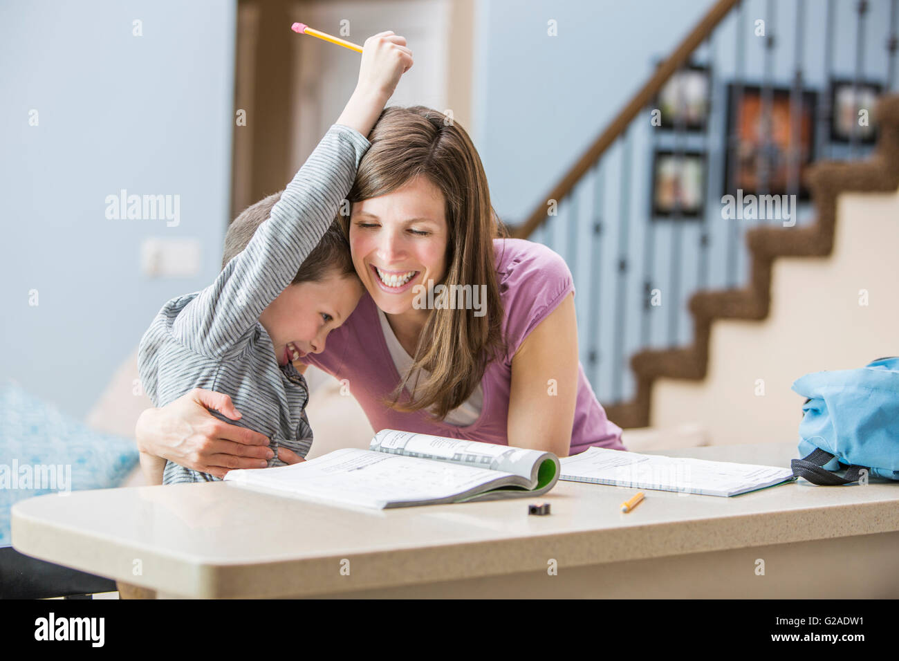 Sorridente abbracciando madre figlio (6-7) svolgendo compiti Foto Stock