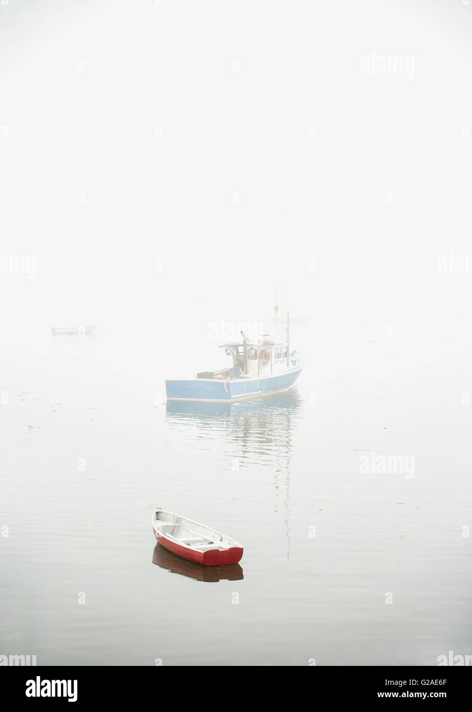 Barche nella nebbia galleggiante sull'acqua Foto Stock