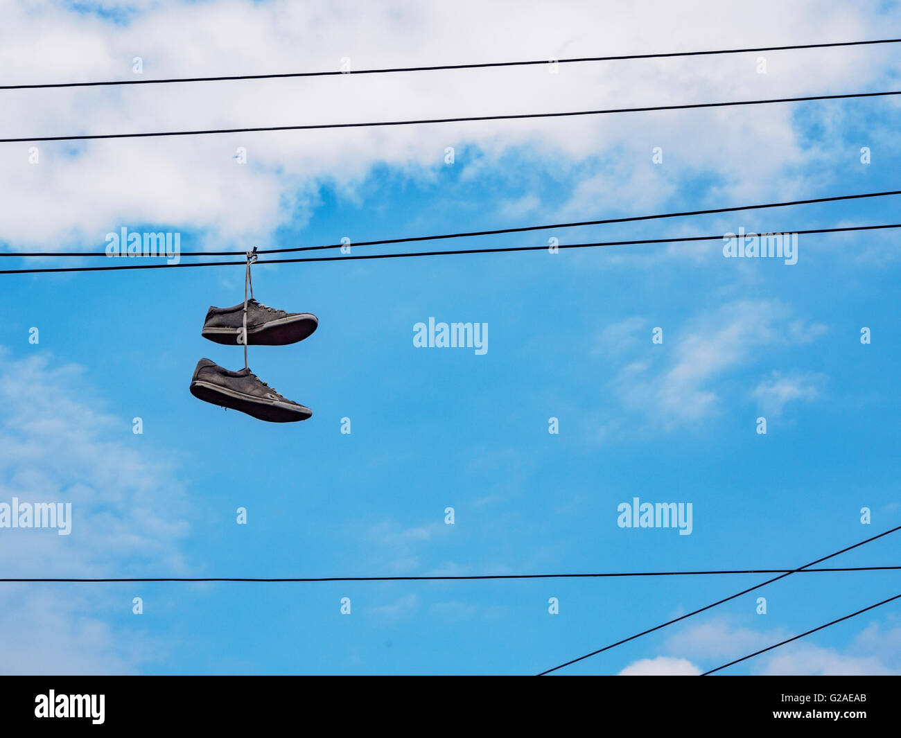Paio di scarpe appeso su linee via cavo contro sky Foto Stock