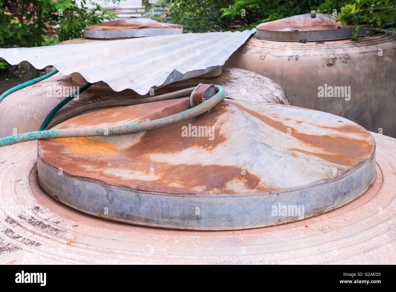 Grande acqua Vaso con coperchio di metallo vicino al lato di una casa di campagna in Thailandia. Foto Stock