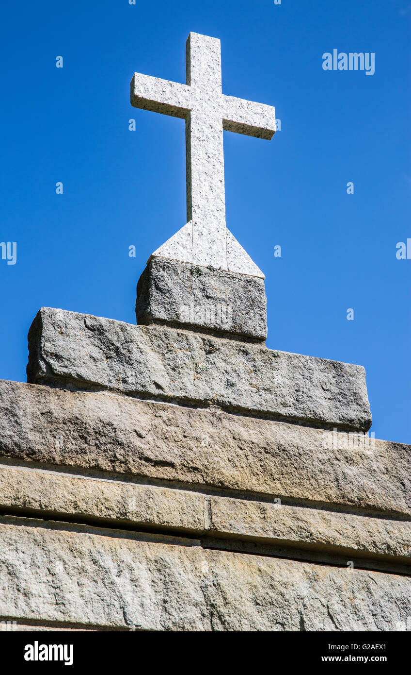 Liscio grigio chiaro quasi bianco granito croce sulla sommità del ruvida terra conci di pietra di tono struttura di mattoni contro il chiaro cielo blu senza nuvole Foto Stock