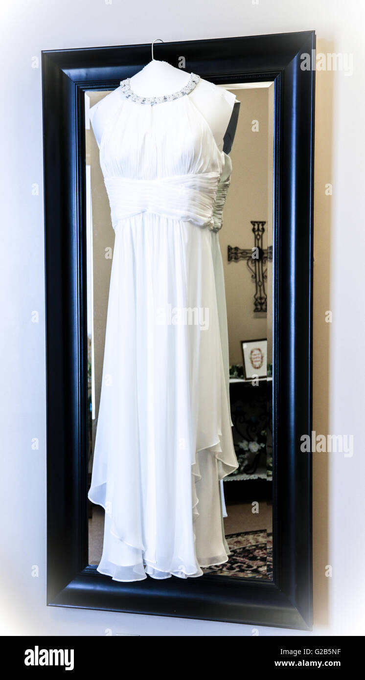 Abito da sposa appeso sullo specchio Foto Stock