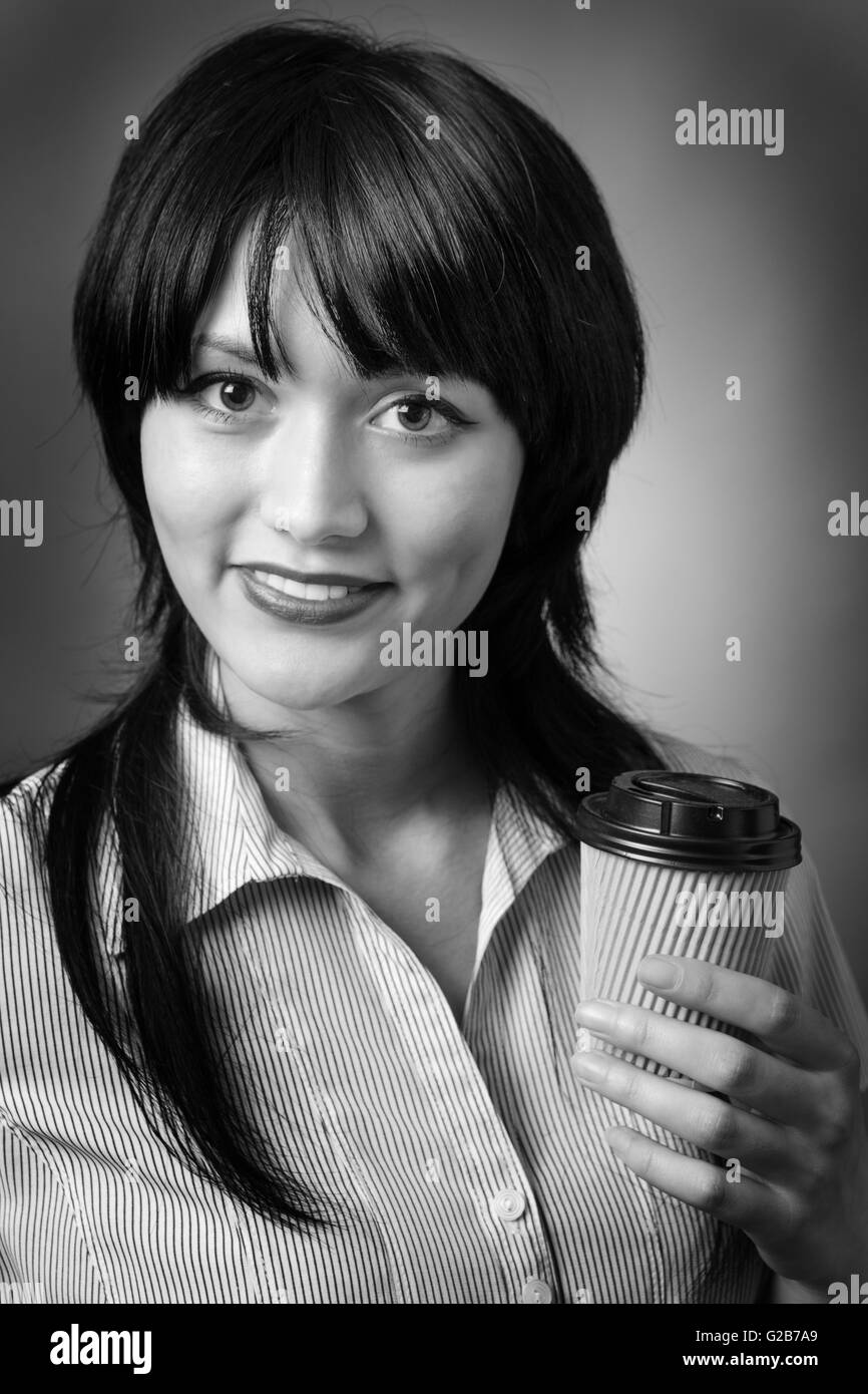 Close up ritratto di un attraente giovane donna di affari con un take away bevanda calda tazza . Girato su sfondo grigio. Foto Stock