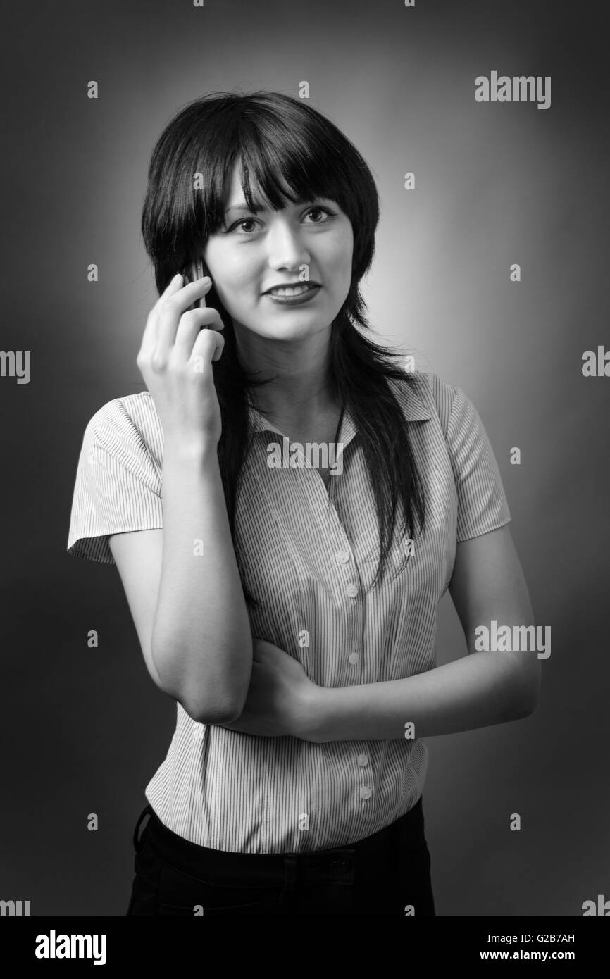 Close up ritratto di un attraente giovane donna business parlando sul suo telefono cellulare. Girato su sfondo grigio. Foto Stock