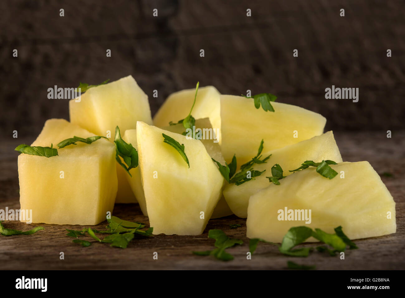 Pila di fettine di patate con prezzemolo sul taglio da cucina in legno marrone board Foto Stock