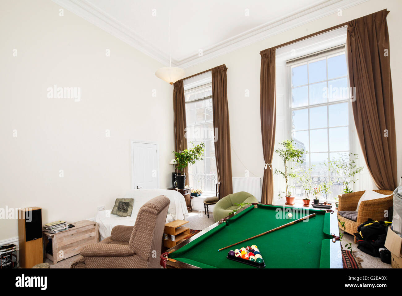 Cavendish Place, Brighton. Affollata area salotto con sedie e tavolo da biliardo. Grandi finestre con tirata indietro tende. Foto Stock