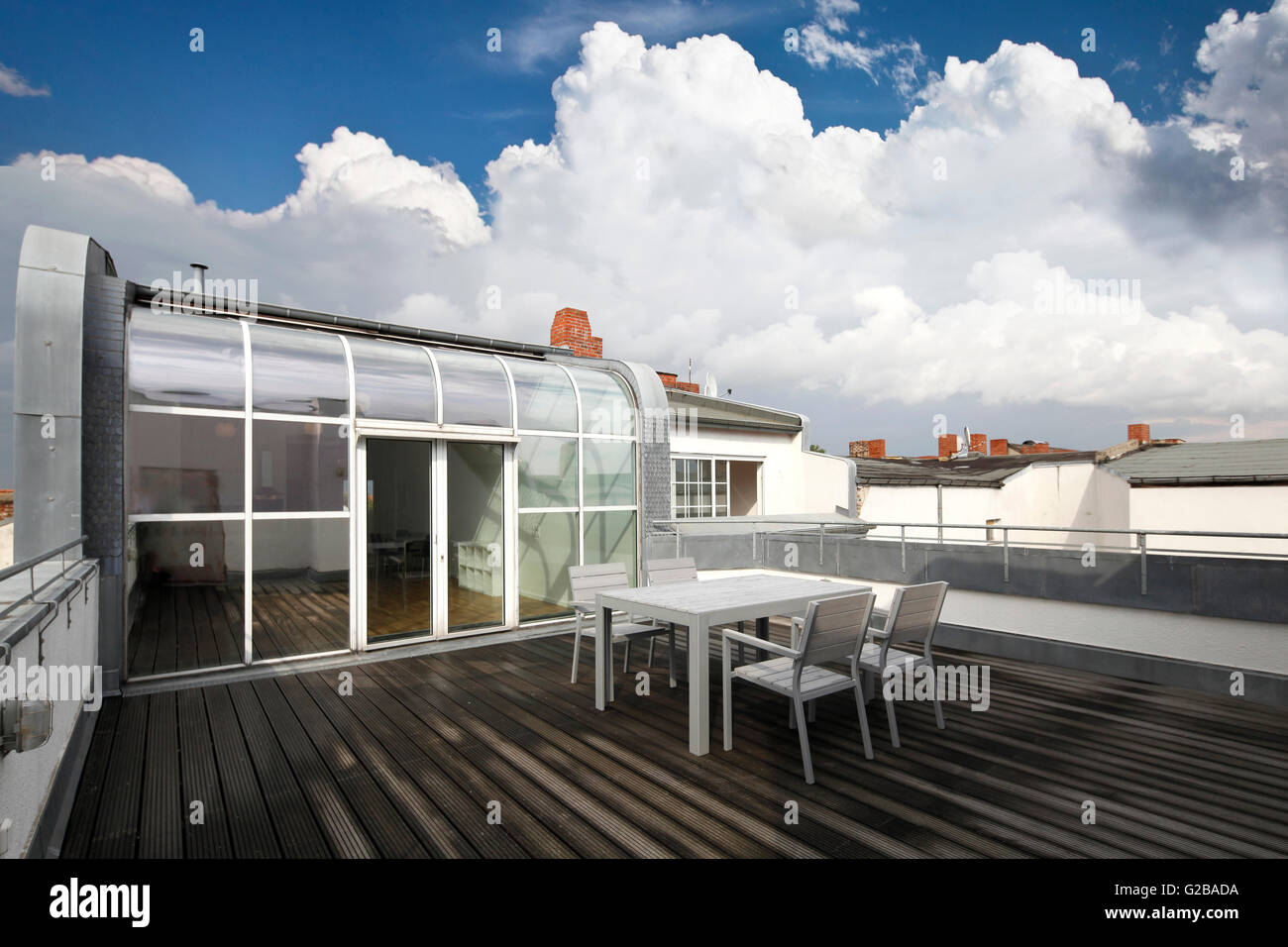 Conversione di Dach o soppalco in Reichenberger Strasse, Kreuzberg. Legno moderno decking contemporanea con tavolo da pranzo e sedie. Vetro le porte del patio. Curvato finestre da pavimento a soffitto. Foto Stock