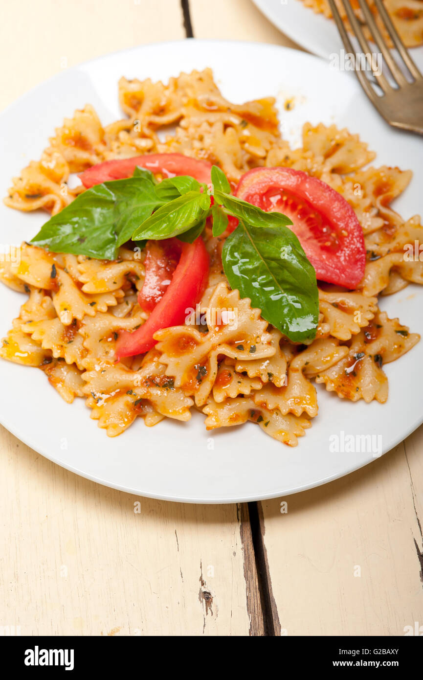 La pasta italiana Le farfalle butterfly bow tie-in pomodoro con salsa al basilico bianco su tavola in legno rustico Foto Stock