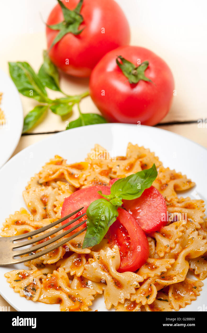 La pasta italiana Le farfalle butterfly bow tie-in pomodoro con salsa al basilico bianco su tavola in legno rustico Foto Stock