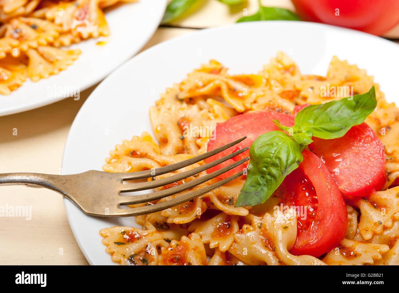 La pasta italiana Le farfalle butterfly bow tie-in pomodoro con salsa al basilico bianco su tavola in legno rustico Foto Stock