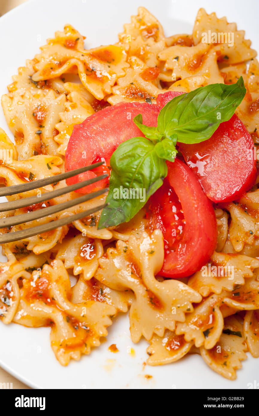 La pasta italiana Le farfalle butterfly bow tie-in pomodoro con salsa al basilico bianco su tavola in legno rustico Foto Stock