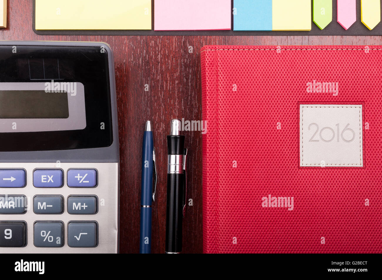 Vista dettagliata del diario di business, calcolatrice e forniture per ufficio organizzata sul banco in legno Foto Stock
