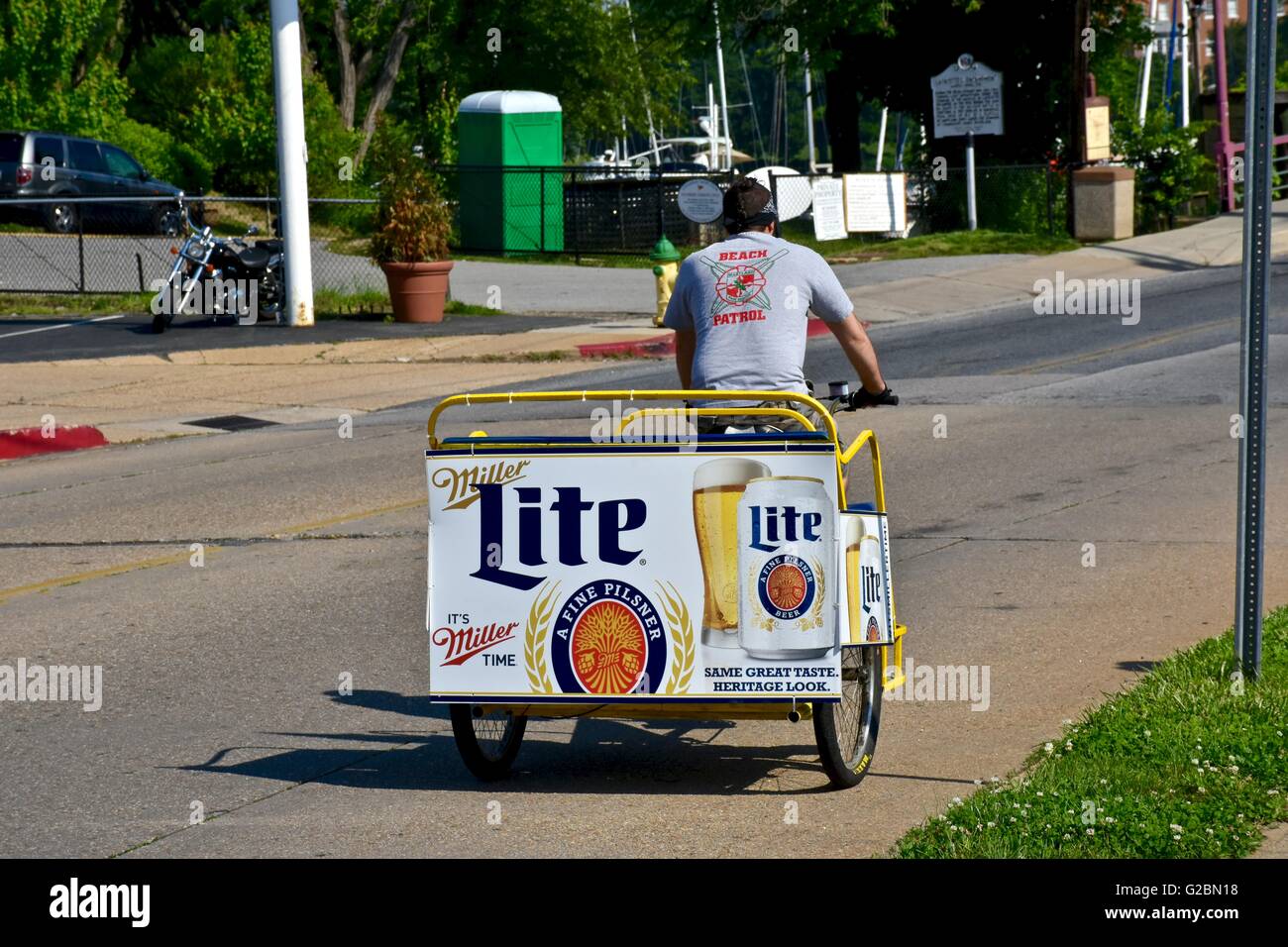 Un uomo in sella a una moto taxi con un Miller Lite poster sul retro del carrello Foto Stock