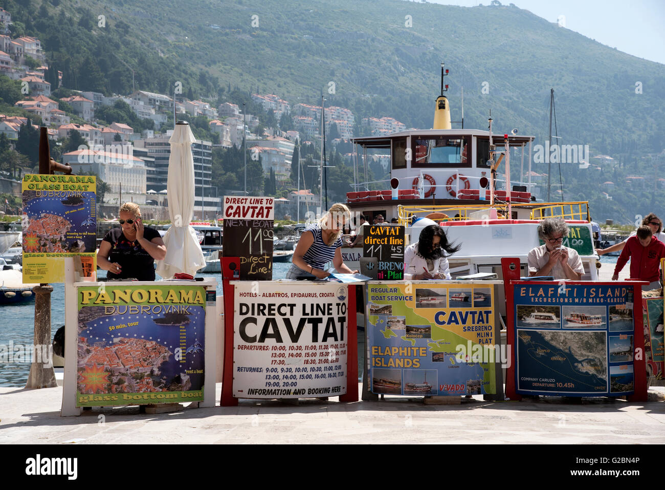 La gente di vendite vendita di gite in barca per i turisti dalle loro scrivanie sul porto di Dubrovnik Croazia Foto Stock