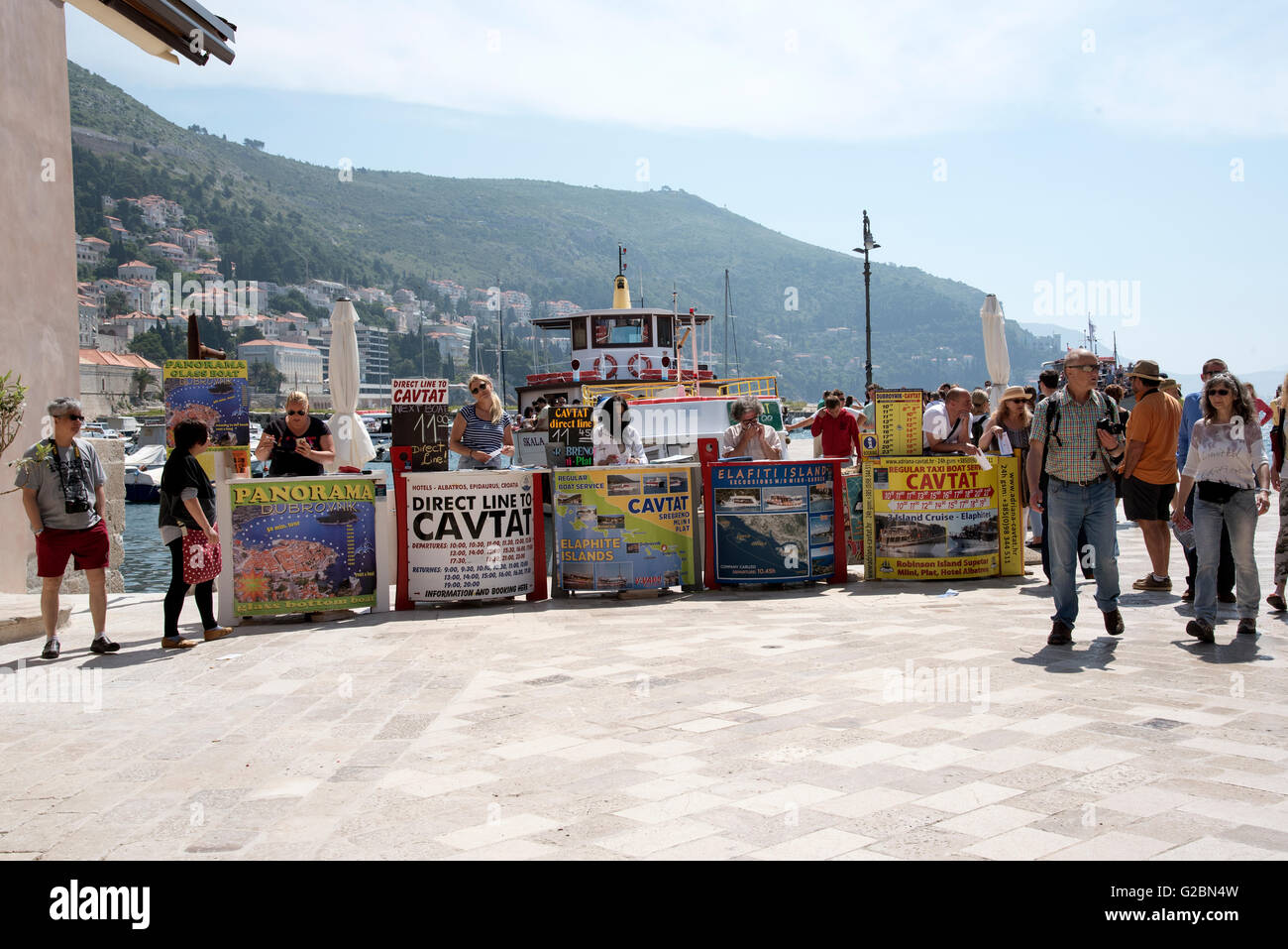 La gente di vendite vendita di gite in barca per i turisti dalle loro scrivanie sul porto di Dubrovnik Croazia Foto Stock