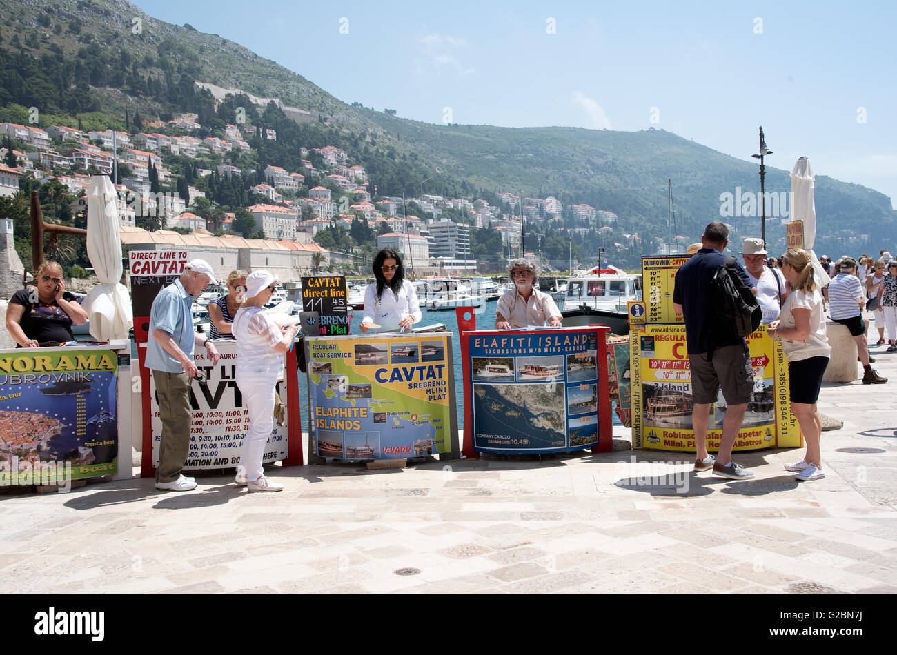 La gente di vendite vendita di gite in barca per i turisti dalle loro scrivanie sul porto di Dubrovnik Croazia Foto Stock