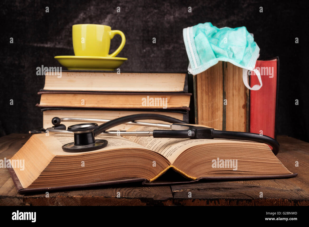 Uno stetoscopio sul libro aperto e caffè sulla pila di libri Foto Stock