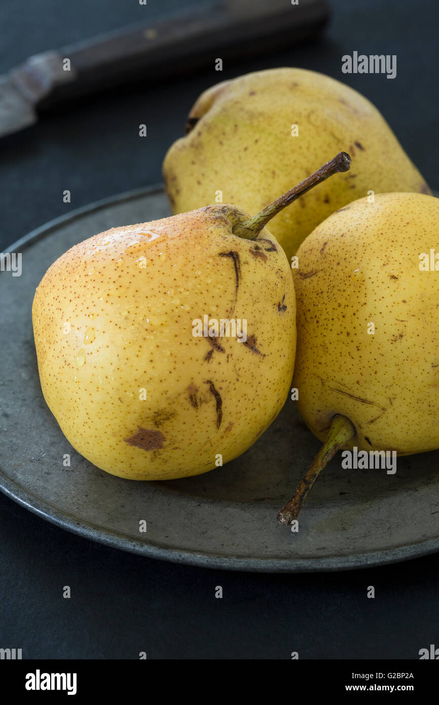 Ancora la vita di pere Comice su una piastra in peltro e uno sfondo scuro. Foto Stock
