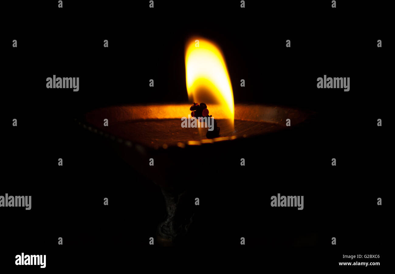 Fiamma dalla lampada a olio scuro dello sfondo deformato stoppino in un tempio indù rituale di preghiera Foto Stock