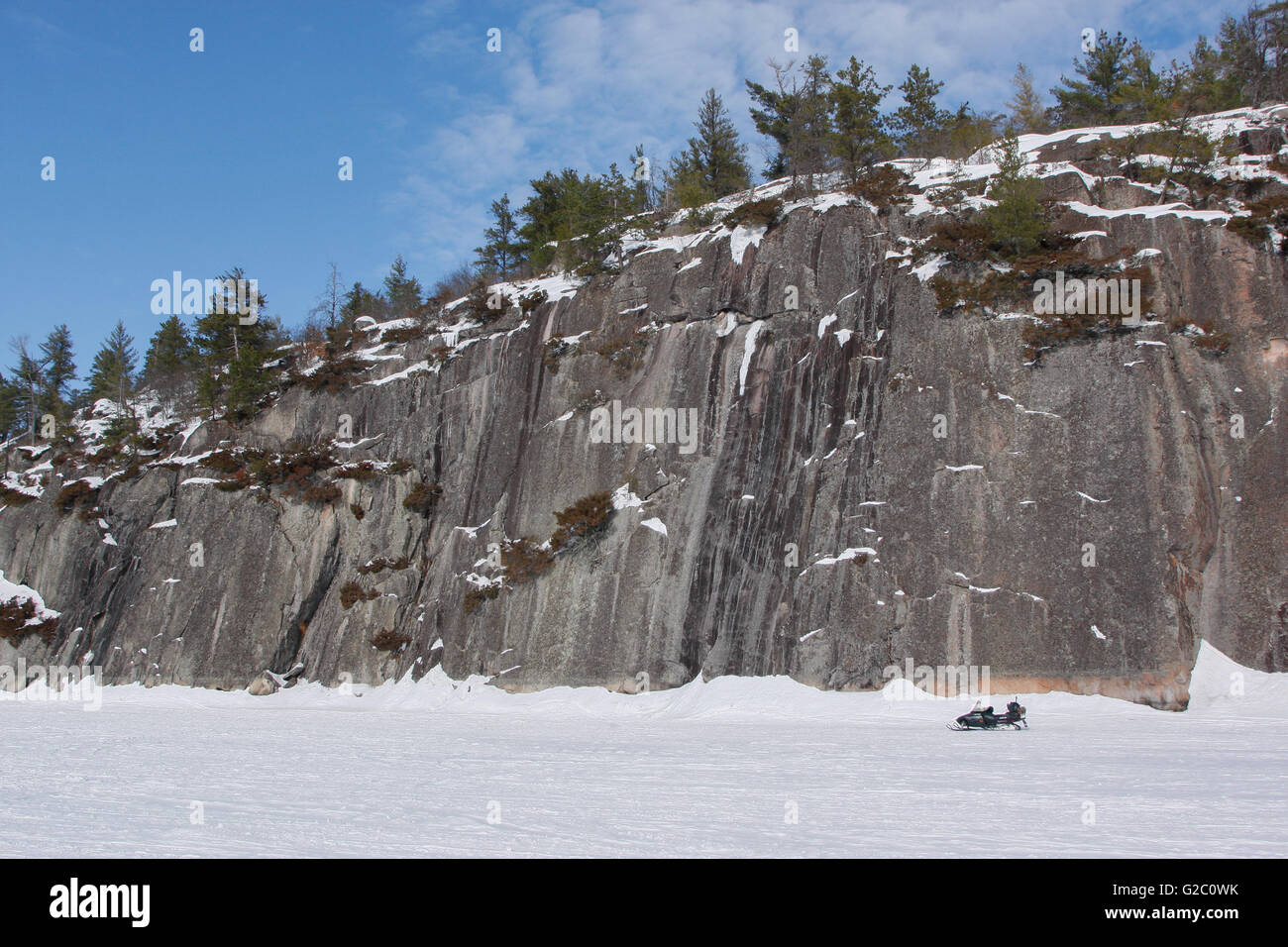 Alta parete di roccia nella baia di erbosa, Sand Point Lago, Parco nazionale Voyageurs, Minnesota, Stati Uniti d'America nani un snowmolbile. Foto Stock