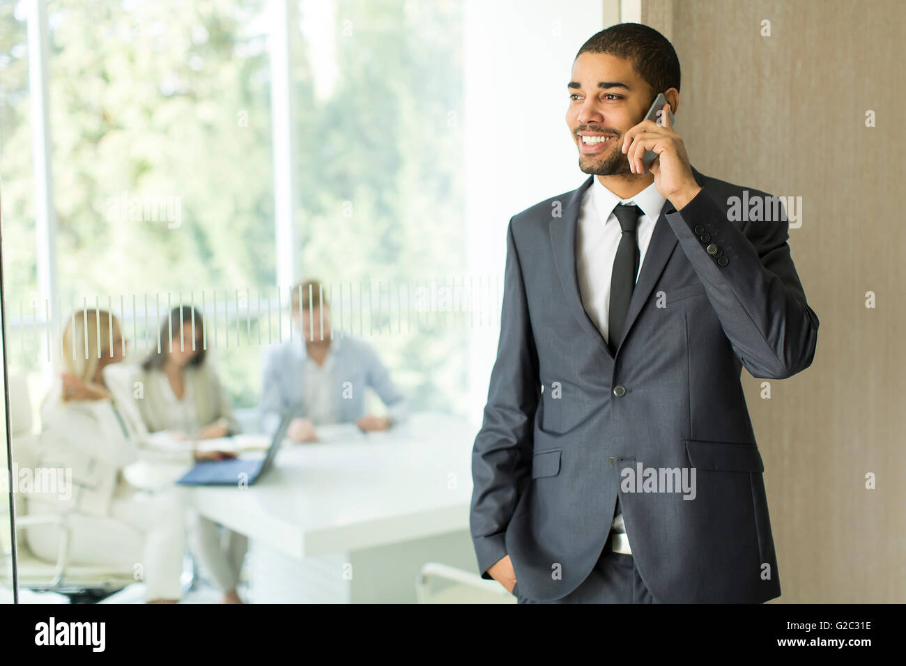Giovane uomo nero con il cellulare in ufficio Foto Stock
