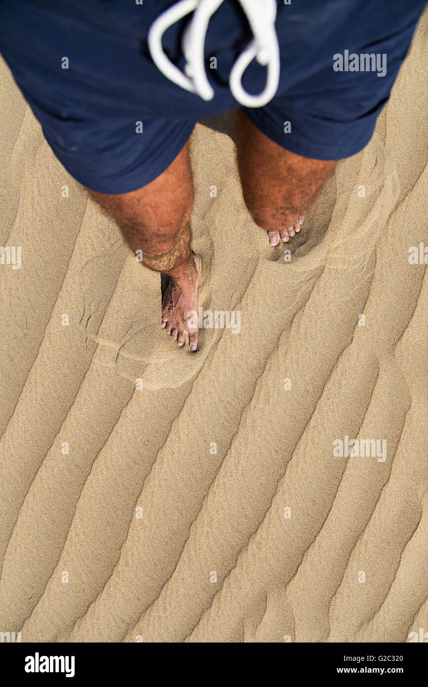 Le gambe di un uomo che cammina e lasciando impronta del piede sulla sabbia Foto Stock