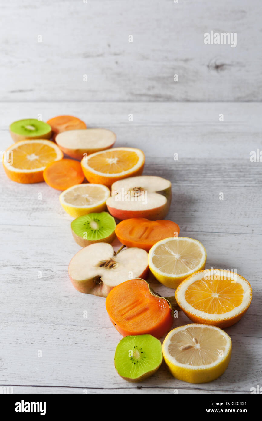 Fette di sani frutti su bianco tavola in legno rustico. L'immagine verticale con copia spazio. Foto Stock
