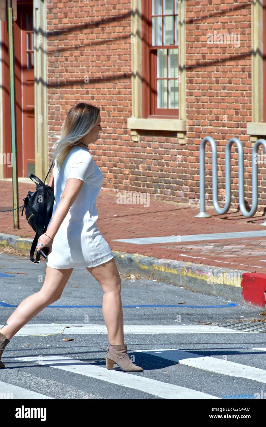 Una bella ragazza in un abito bianco tenendo una borsa nera camminare per la strada Foto Stock