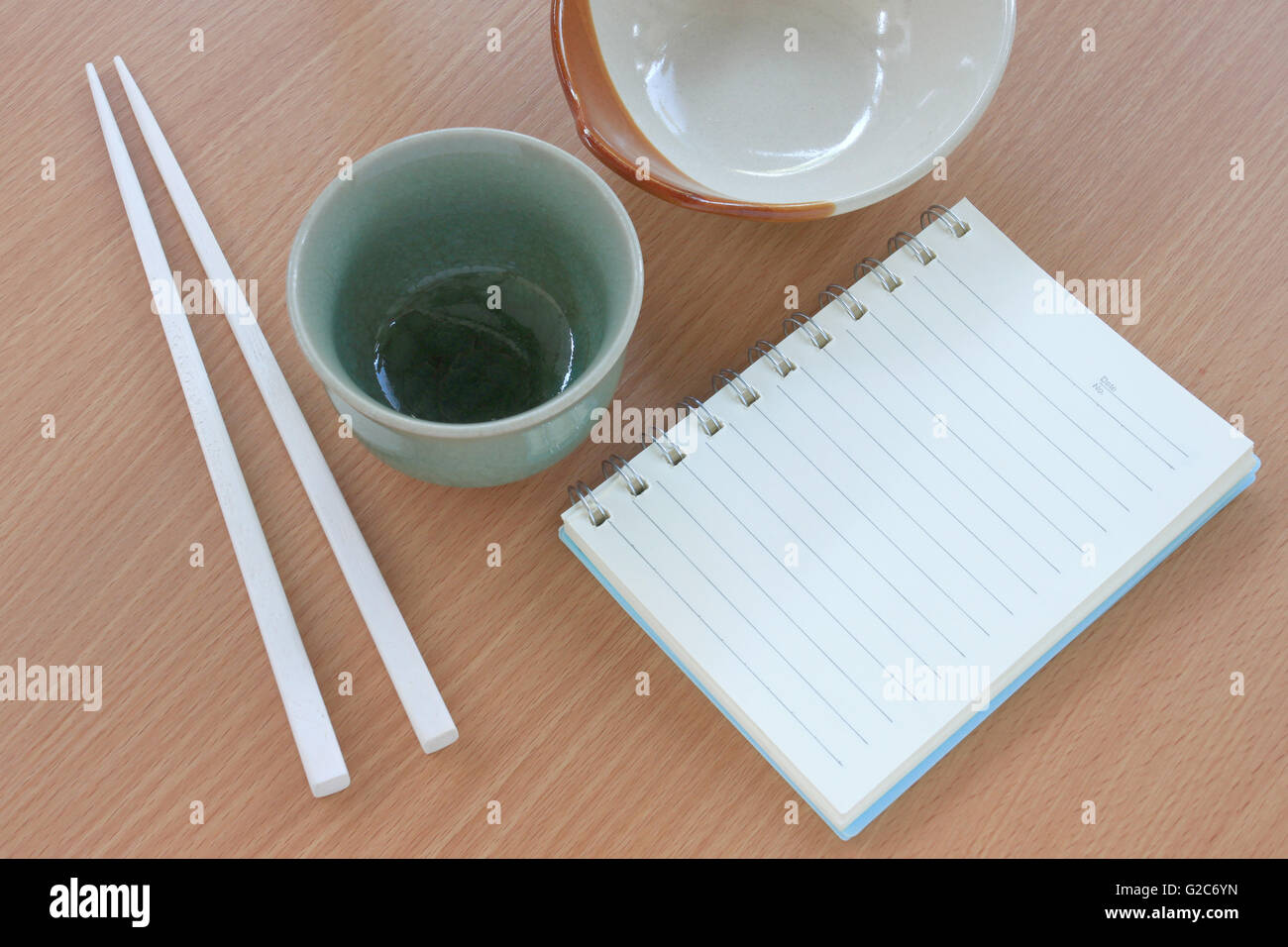 Libro vuoto e la coppa di stile Giapponese sulla tabella degli alimenti. Foto Stock