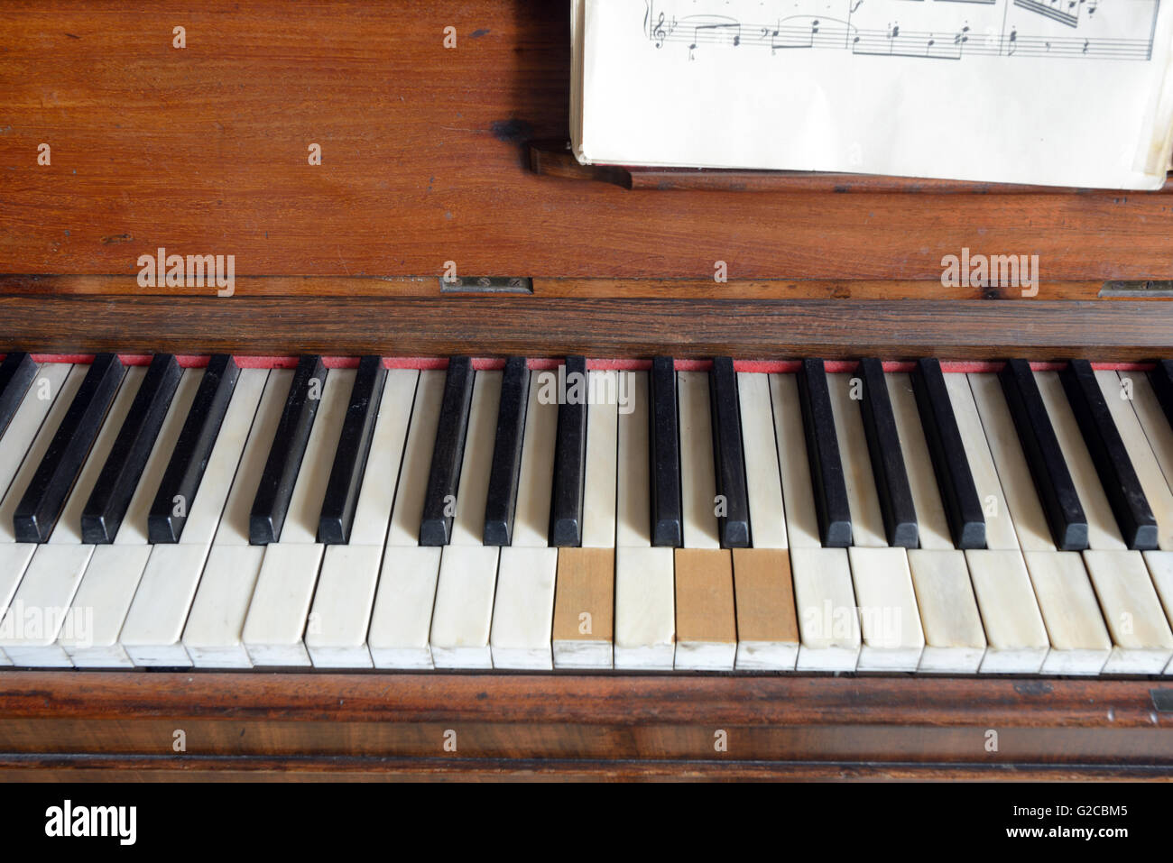 Vecchio pianoforte con tasti mancanti e foglio di musica o cliente Foto Stock