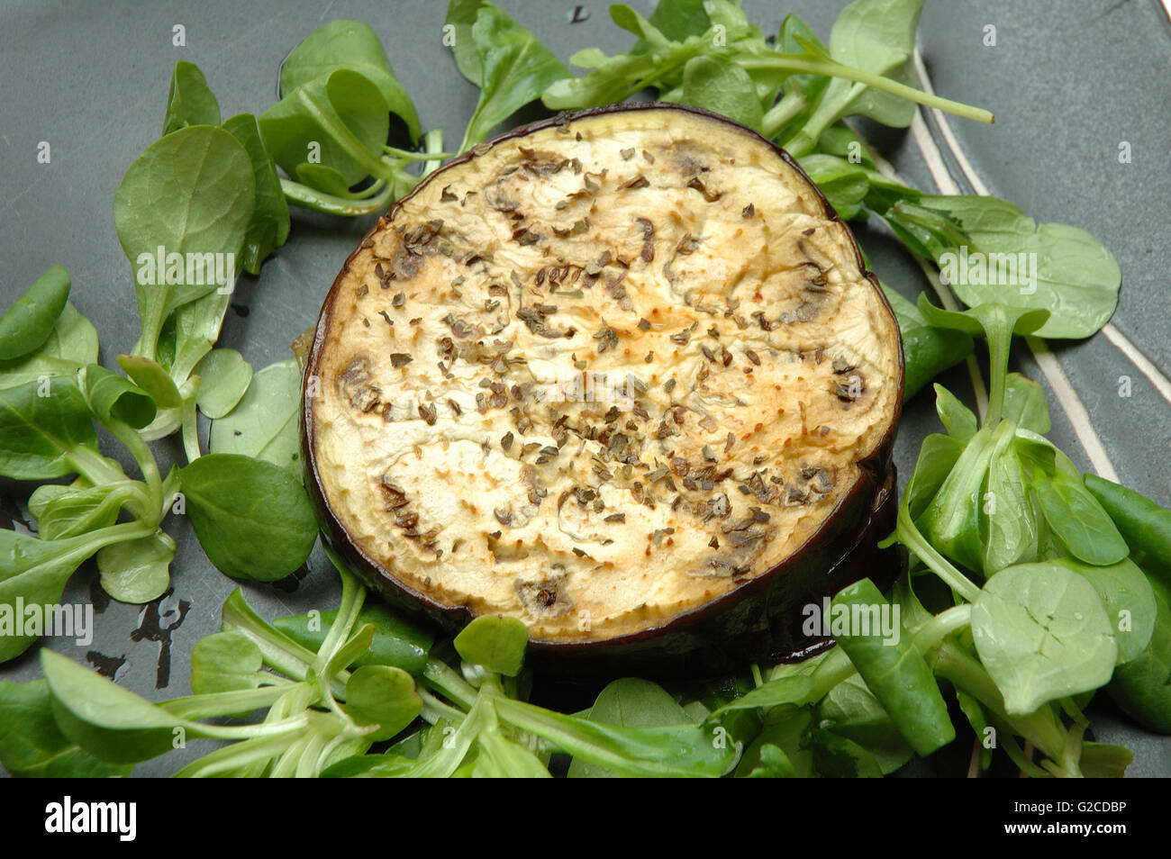 Melanzane al forno con insalata di rucola sulla piastra nera Foto Stock