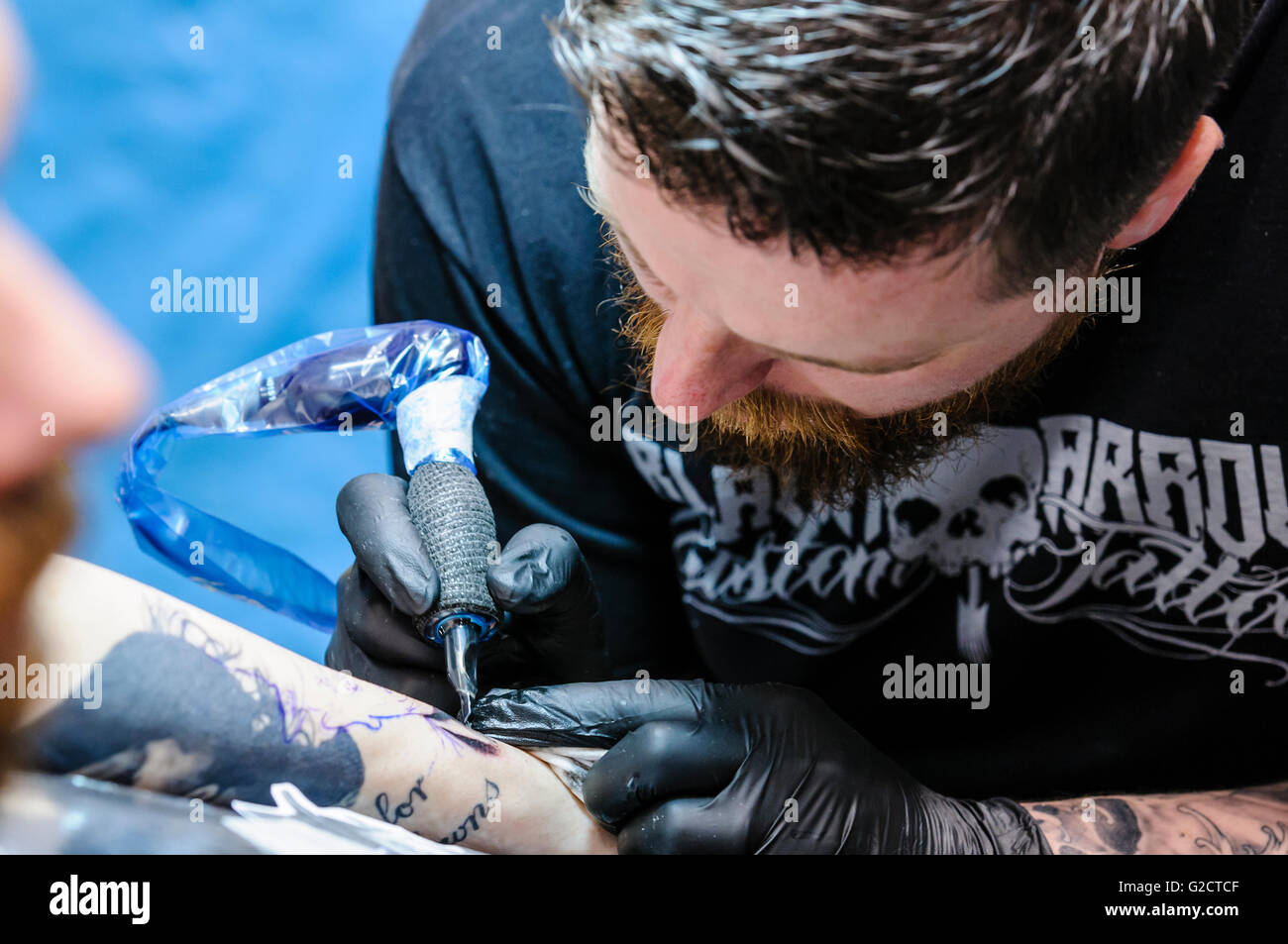 BELFAST, IRLANDA DEL NORD. 28 MAGGIO 2016 - 6 Irlanda del Nord Tattoo Conferenza. Un tatuaggio artista disegna tatuaggio sul braccio di un maschio di cliente. Foto Stock