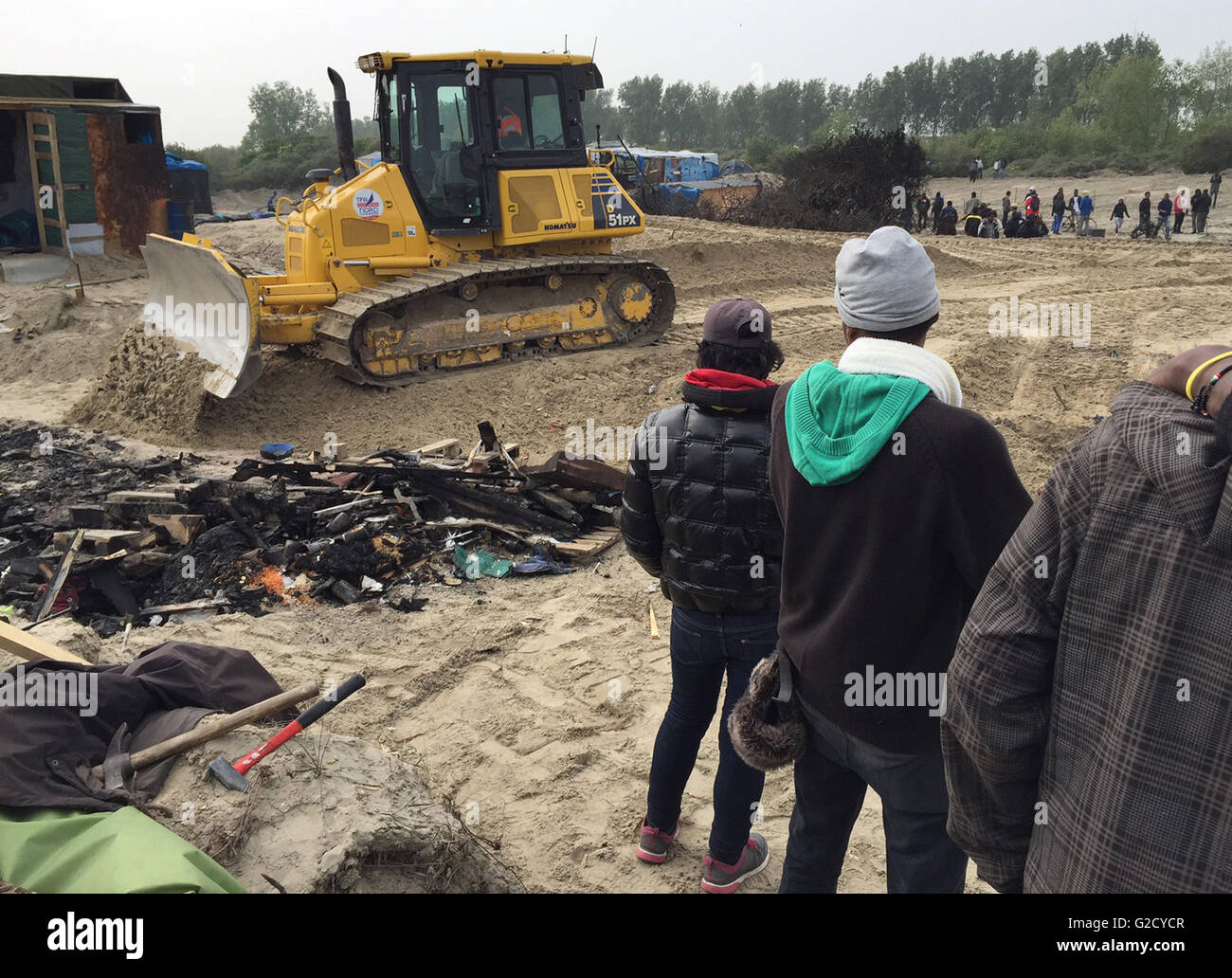 Calais, Francia. 27 Maggio, 2016. I rifugiati di guardare un bulldozer la guida sul sito del campo migrante soprannominato "Jungle' nella periferia di Calais, Francia, 27 maggio 2016. Quaranta persone sono rimaste ferite in una rissa al campo profughi, le autorità locali ha detto. Diversi rifugi sono stati bruciati. Foto: Anna Psaroudakis/dpa/Alamy Live News Foto Stock